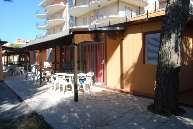 Terrazza esterna con tavoli bianchi vicino a un edificio.