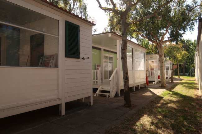Bungalow bianchi tra gli alberi in un campeggio.