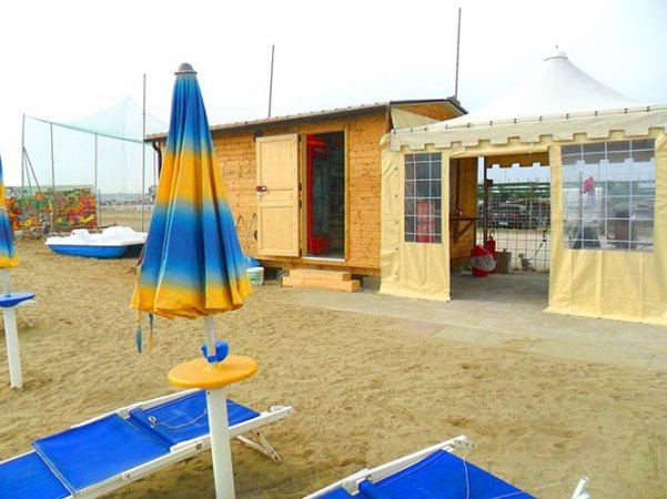Ombrelloni blu e gialli vicino a un capanno sulla spiaggia.