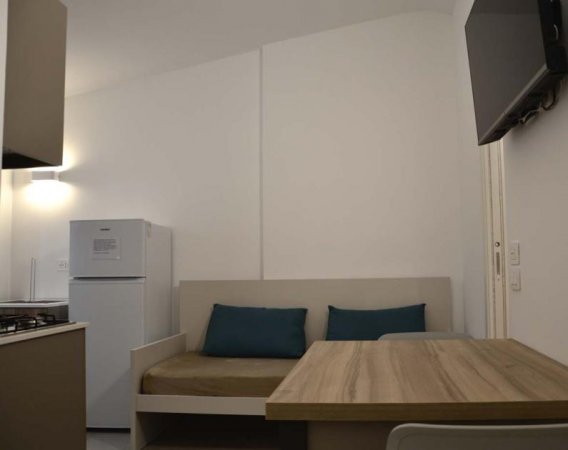 Soggiorno con divano, tavolo e frigorifero.