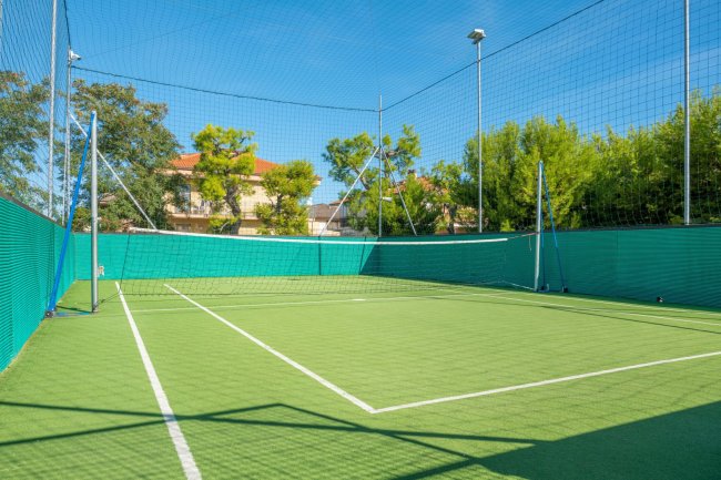 Un campo da tennis con rete e pareti verdi.