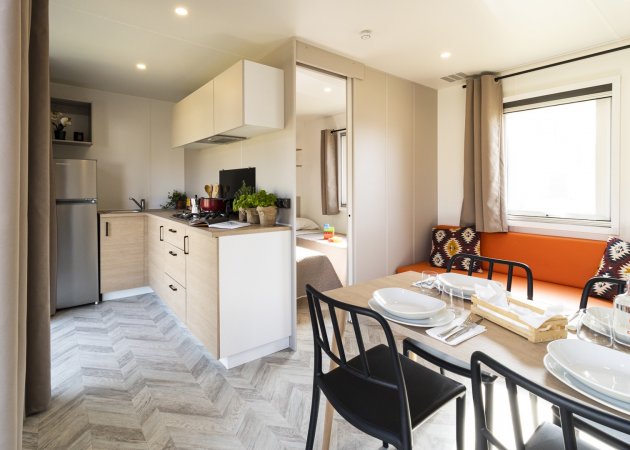 Una cucina moderna e luminosa con tavolo apparecchiato e divano arancione.