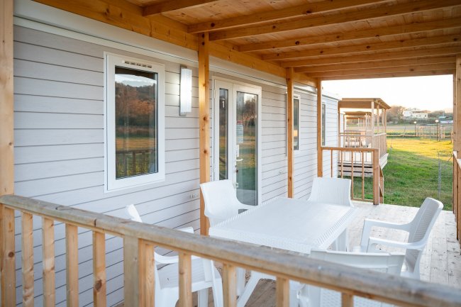 Veranda di legno con sedie e tavolo bianco.