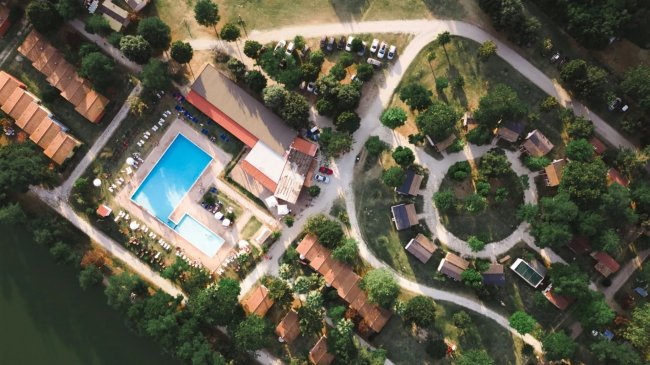 Vista aerea di un complesso con piscine, strade e casette immerse nel verde.