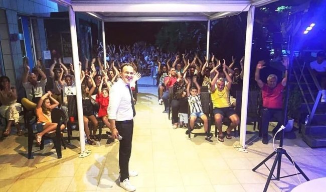 Persona su palco con pubblico entusiasta.