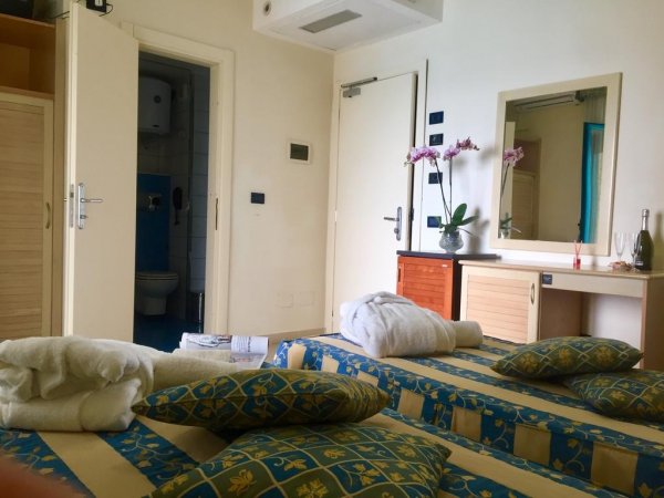 Camera da letto con letto, bagno e tocchi di fiori viola.