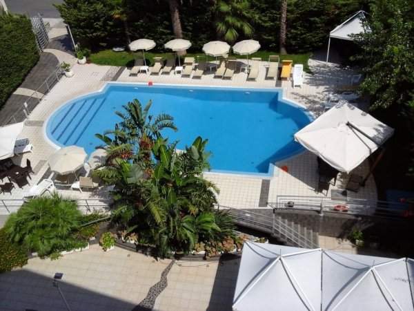 Vista dall'alto di una piscina circondata da lettini e ombrelloni.