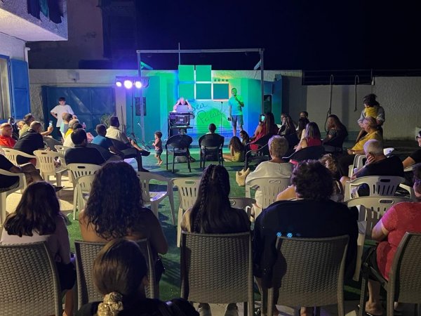 Spettacolo serale all'aperto con pubblico seduto.