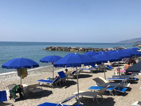 Spiaggia con ombrelloni blu e lettini.