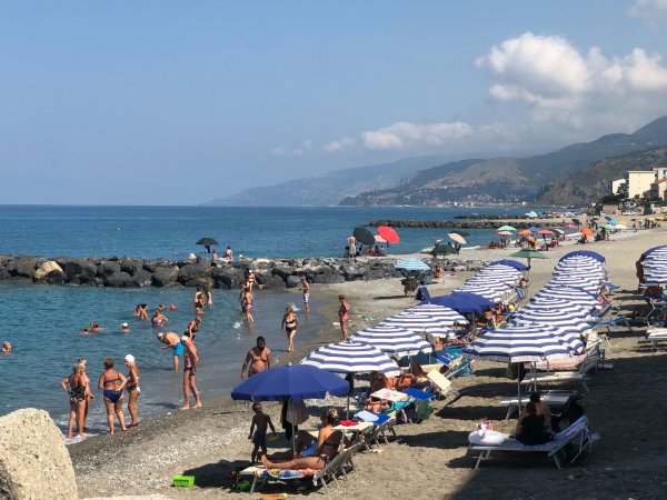 Spiaggia affollata con ombrelloni e bagnanti.
