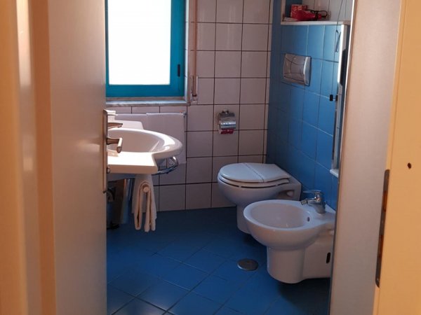 Bagno con sanitari e piastrelle blu.