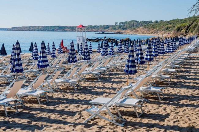 Sedie e ombrelloni blu su una spiaggia sabbiosa.