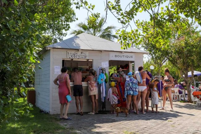 Persone in costume da bagno attorno a un chiosco sulla spiaggia.