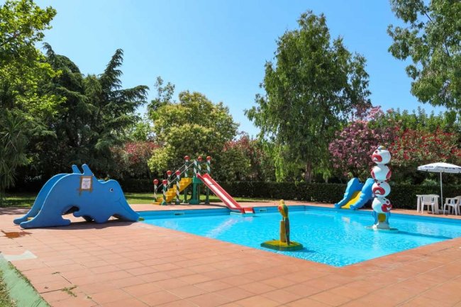 Piccola piscina con scivoli colorati e decorazioni a forma di animali per bambini.