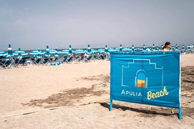 Spiaggia con ombrelloni blu e un cartello che dice 