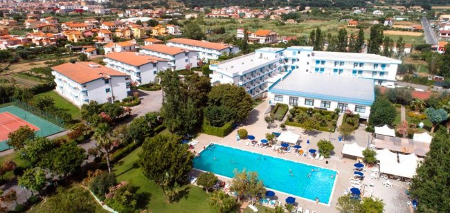 Veduta dall'alto di un complesso turistico con piscina e campi da tennis.