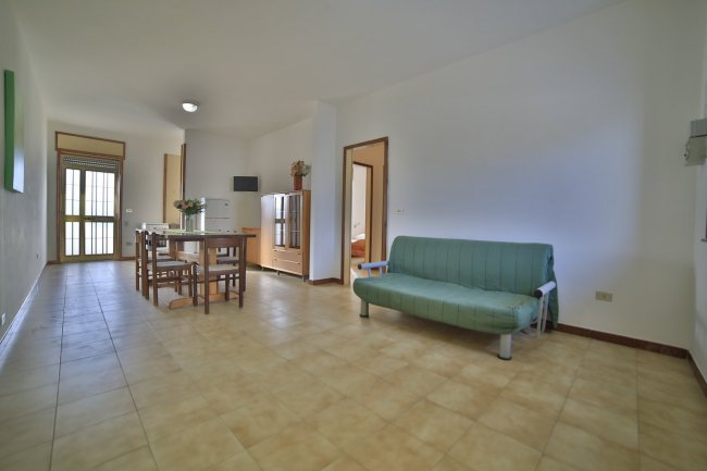 Stanza con divano verde e tavolo con sedie.