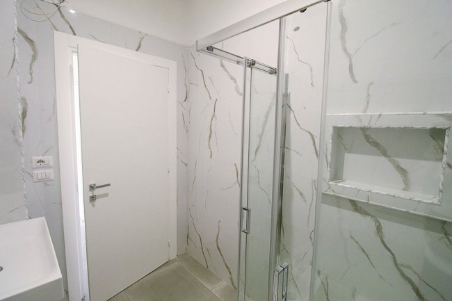 Bagno moderno con doccia e piastrelle marmoree.