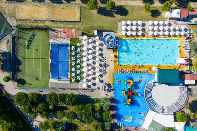 Vista dall'alto di una piscina con ombrelloni e giochi per bambini.