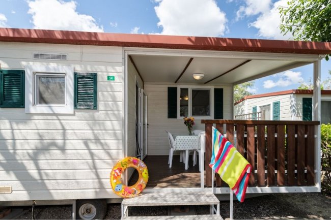 Veranda con tavolo, salvagente appeso, teli colorati.