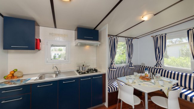 Cucina blu, tavolo apparecchiato, divano a righe blu.