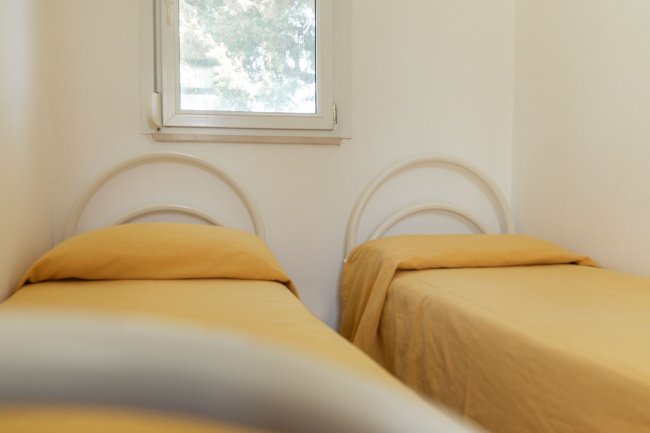 Due letti singoli con copriletti gialli, finestra sullo sfondo.