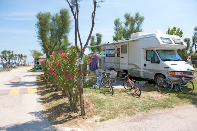 Un camper con biciclette parcheggiato vicino a piante fiorite.