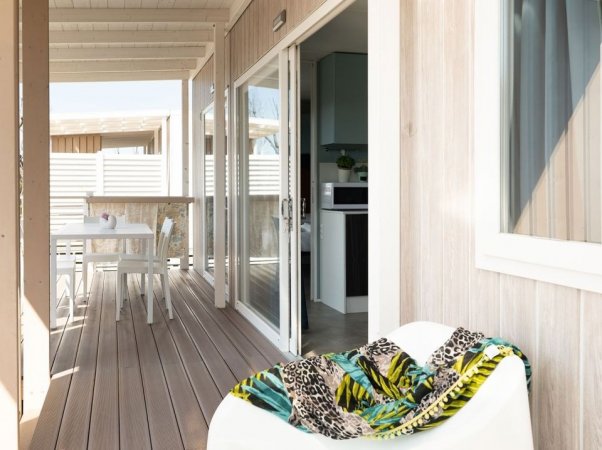 Terrazza con tavolino e sedie, aperta sull'interno.