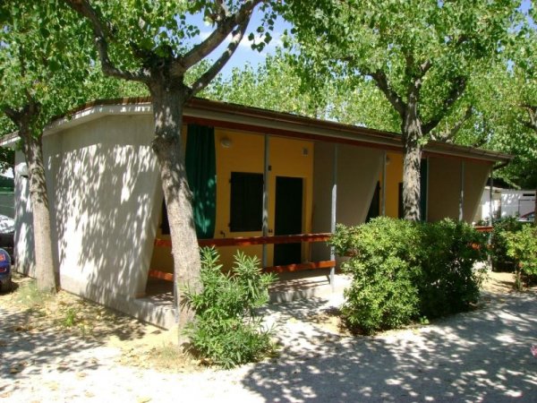 Bungalow con veranda ombreggiata da alberi.