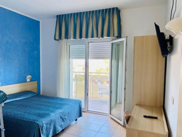 Camera d'hotel con letto e balcone vista giardino.