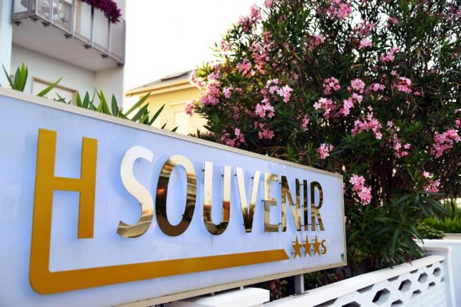 Insegna di un albergo con fiori rosa accanto.