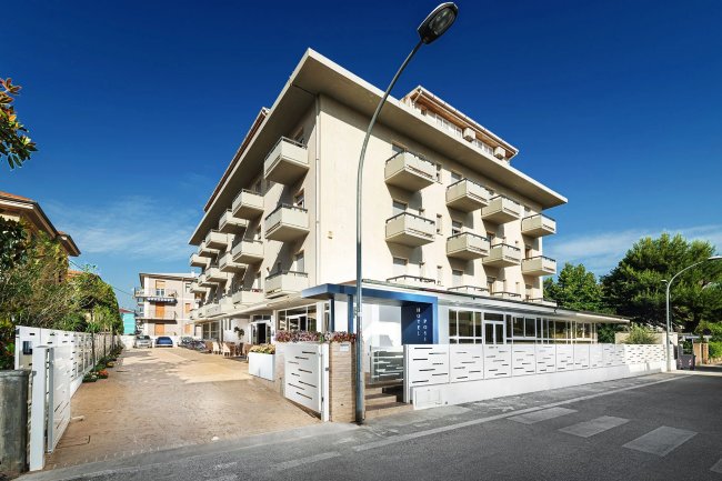 Edificio bianco con balconi su una strada.