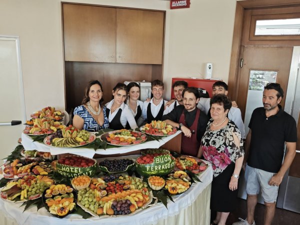 Tavolo con vassoi di frutta e persone sorridenti.