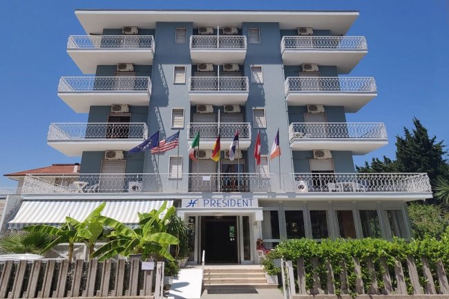 Facciata di un hotel blu con balconi bianchi.