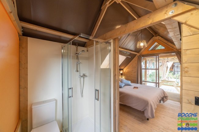 Camera mansardata in legno con letto e bagno con doccia.