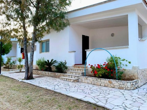 Casa bianca con roseto e arco azzurro.