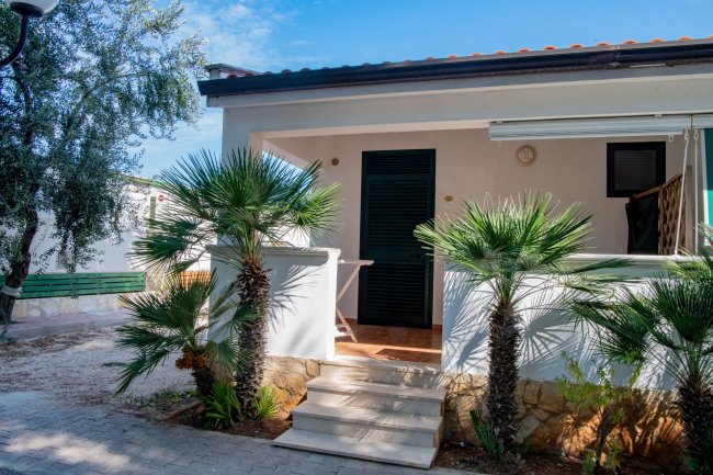 Casa bianca con veranda e palme.