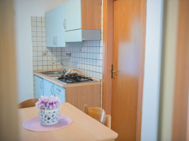 Cucina con tavolo, fornelli e fiori su un centrino.