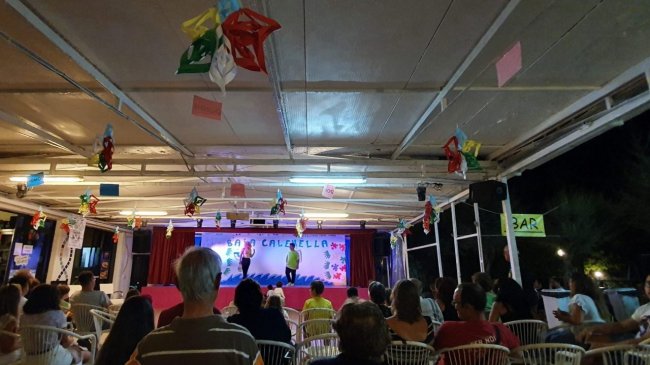 Serata in un locale con palco e pubblico seduto.