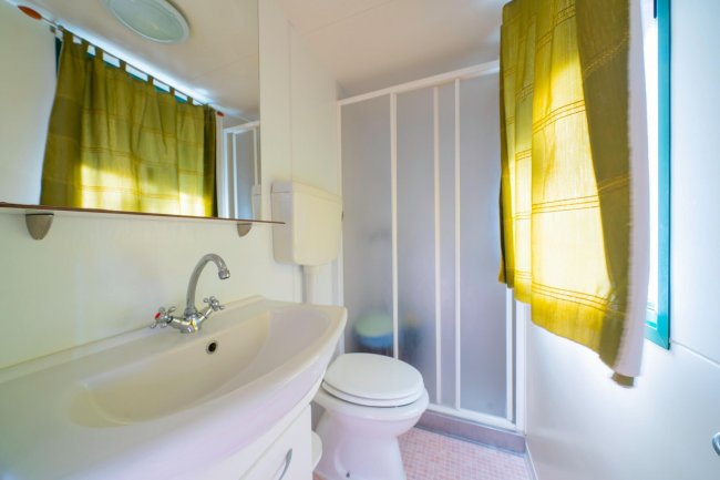 Bagno con tenda verde, lavabo e doccia.