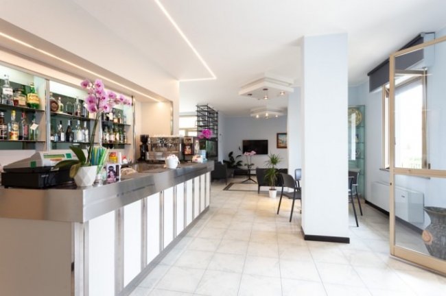 Banco bar elegante con fiori rosa e sedie nere.