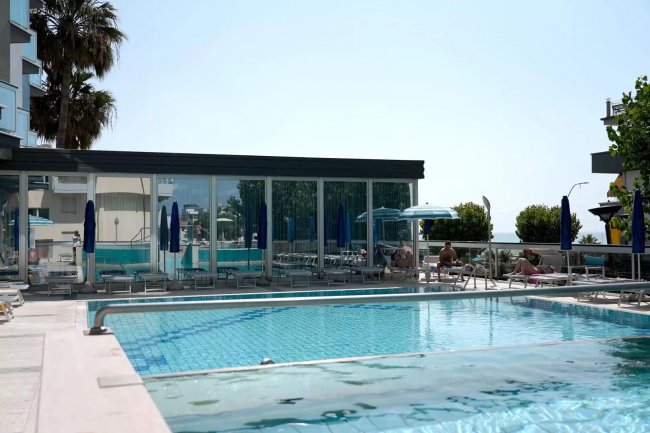 Piscina all'aperto con lettini e ombrelloni.