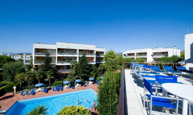 Vista su hotel con piscina e sedie a sdraio.