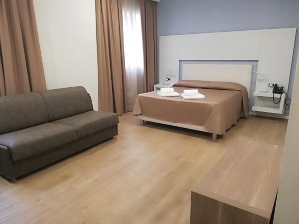 Camera d'albergo con letto, divano e tende marroni.