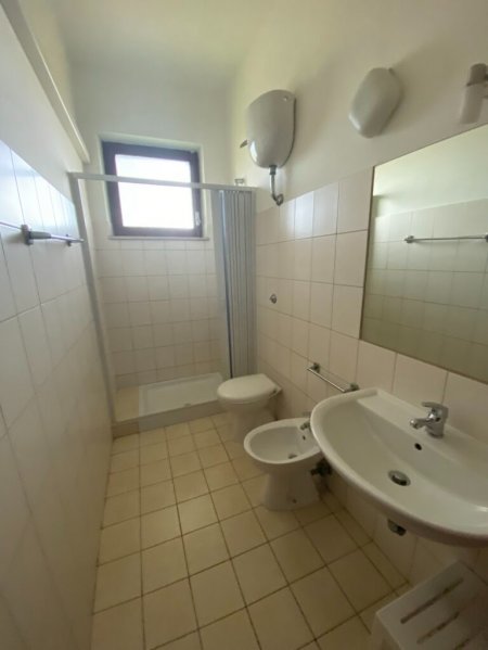 Bagno con doccia, lavandino e WC, finestra sopra.