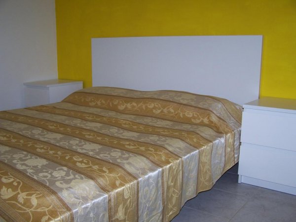 Camera con letto matrimoniale e testiera bianca.