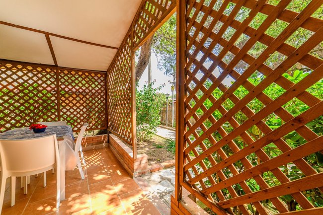 Veranda con tavolo e sedie, grigliato di legno.