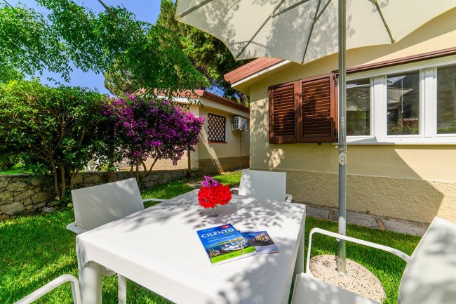 Tavolo bianco in giardino con ombrellone.