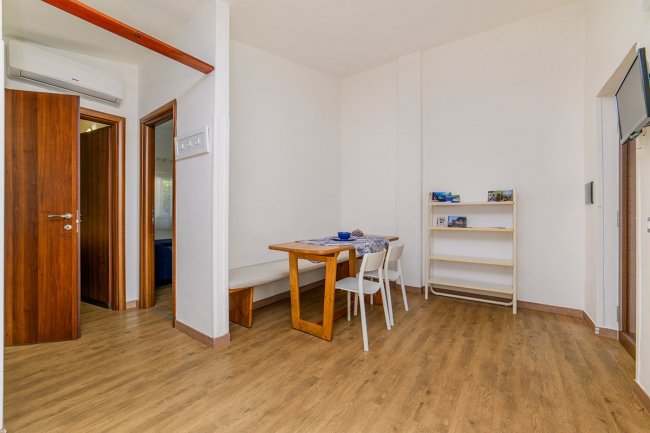 Sala da pranzo con tavolo in legno e sedie bianche.