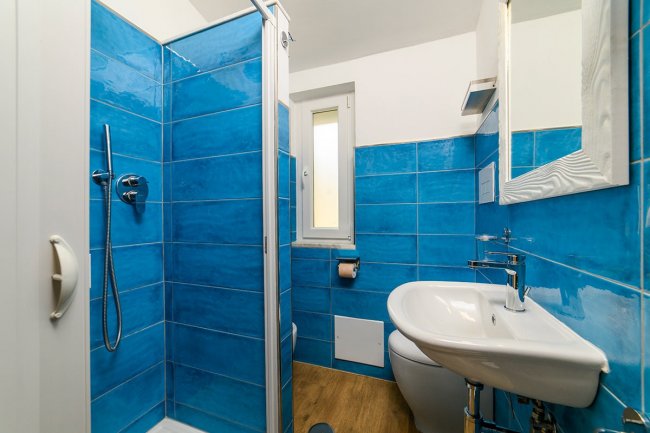 Bagno con piastrelle blu e doccia.